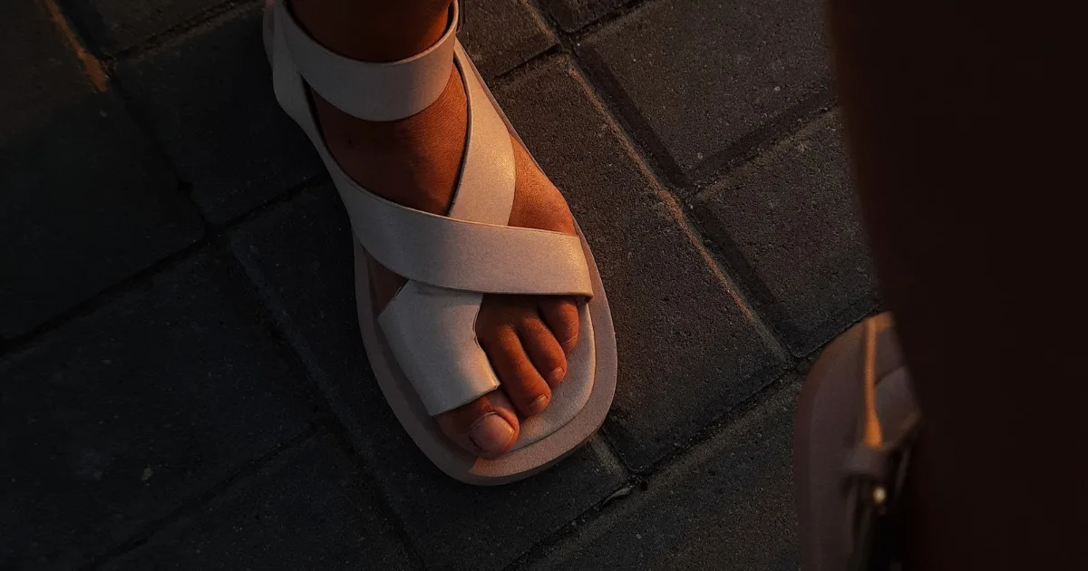 Foot in a contoured slide sandal on dark tile — best sandals for plantar fasciitis, Podiatrist Tested