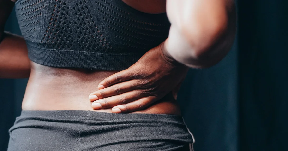 A person holding their lower back - best shoes for back pain, Podiatrist Tested