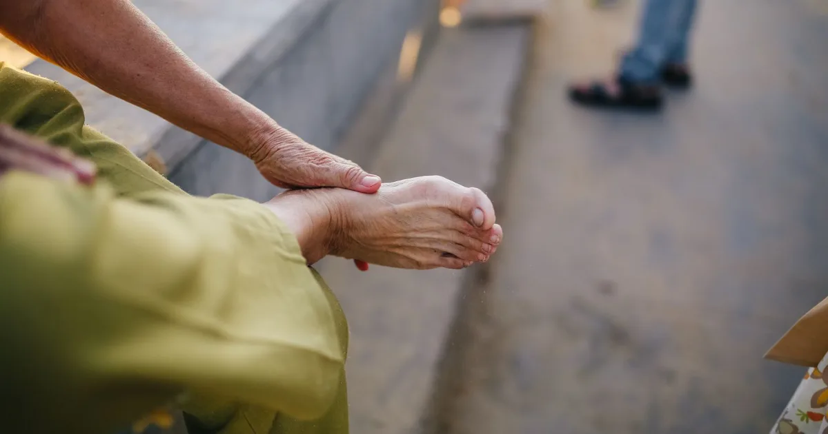 Person seated outdoors easing pressure on a sore heel — best shoes for heel spurs, Podiatrist Tested