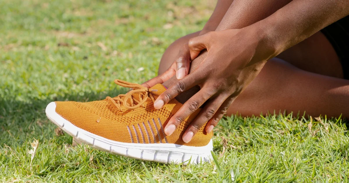 A runner holding the lower leg and foot after exercise - best shoes for shin splints, Podiatrist Tested