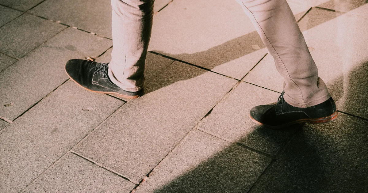 Legs walking across stone paving in flat shoes - best shoes for walking on concrete, Podiatrist Tested