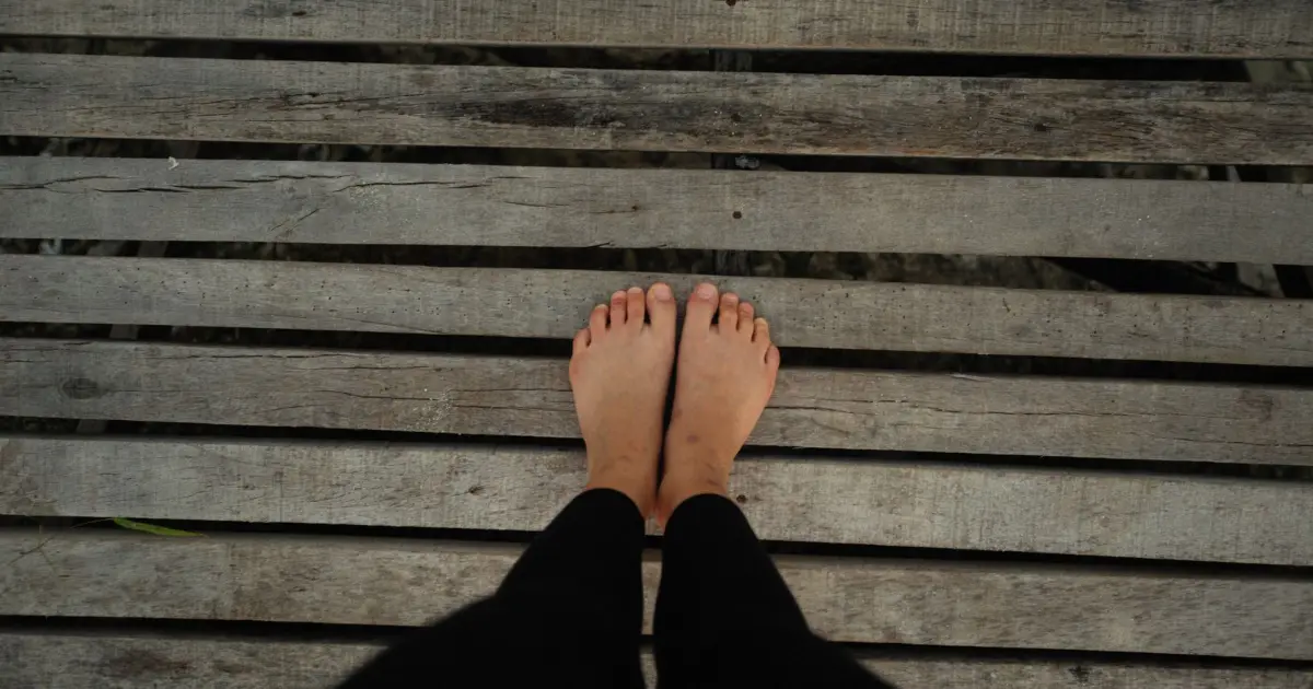 Overhead view of bare feet standing on weathered decking — best shoes for wide feet, Podiatrist Tested
