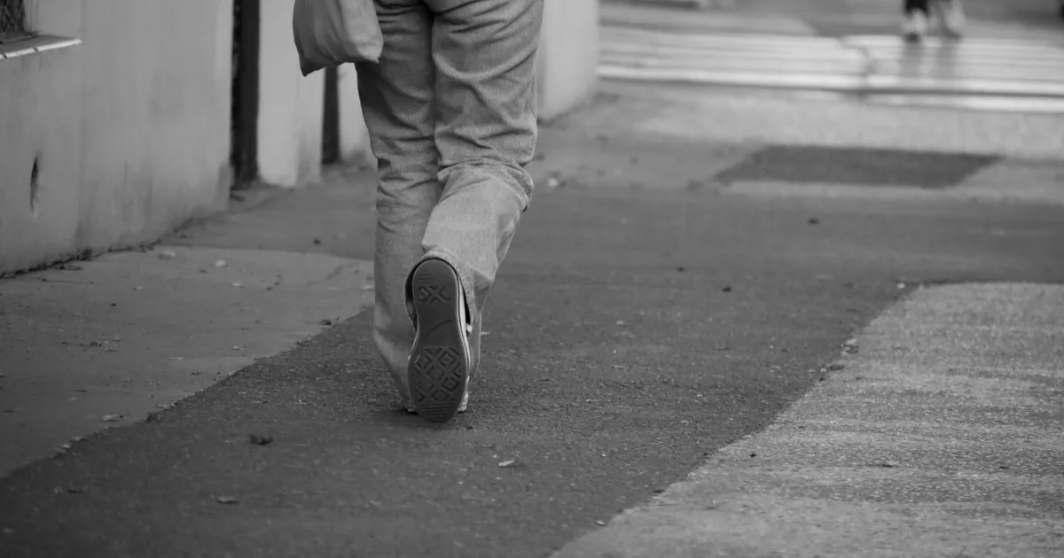 Man mid-stride on a pavement, legs and walking shoes in view — best walking shoes for men, Podiatrist Tested