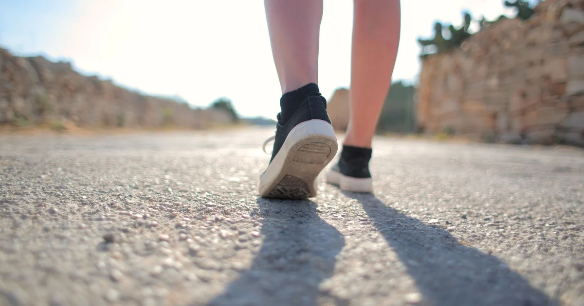 A woman walking on pavement in supportive shoes - best walking shoes for women over 50, Podiatrist Tested
