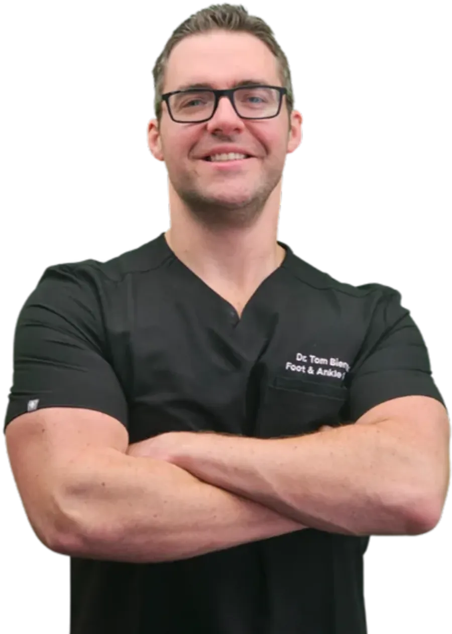 Dr. Tom Biernacki, DPM, FACFAS, double board-certified foot and ankle surgeon, in black scrubs with arms crossed